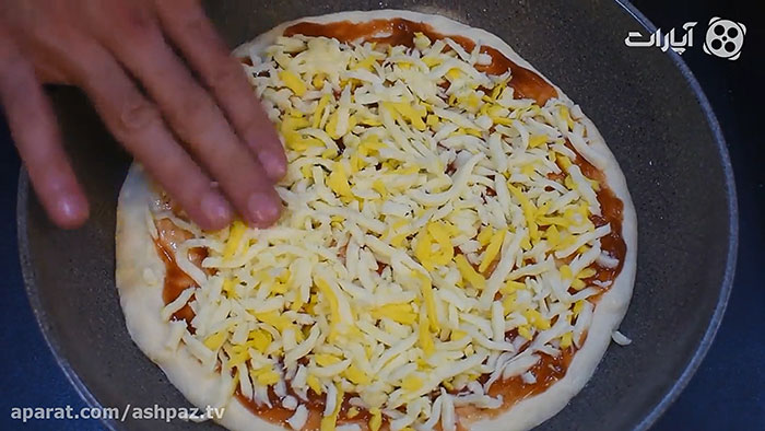 ریختن پنیر پیتزا روی پیتزا پپرونی